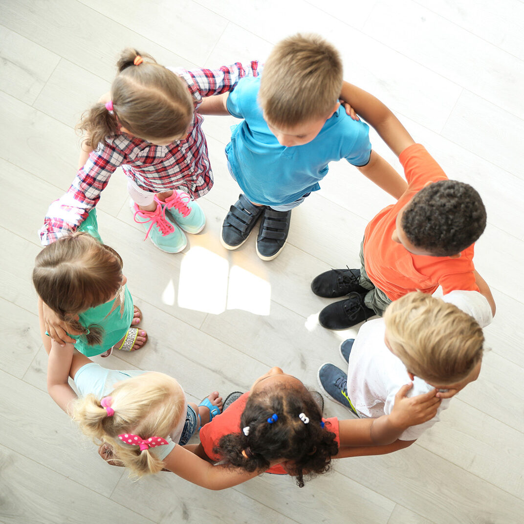 Little children making circle with hands around each other indoors, top view. Unity concept
